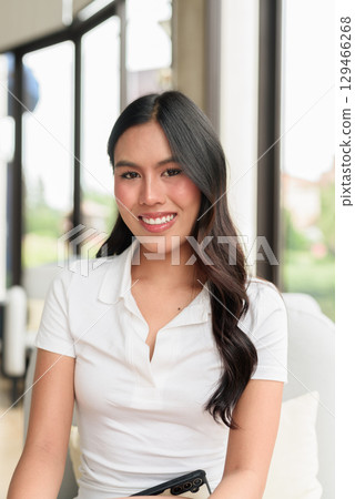 Young Asian woman in white polo shirt indoors, hotel lounge or cafe interior, tourist portrait Young Asian woman in white polo shirt indoors, hotel lounge or cafe interior, tourist portrait 129466268