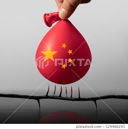 Balloon with China flag floats near sharp spikes, representing looming financial risks in China, economic downturn and investment uncertainty 129466291