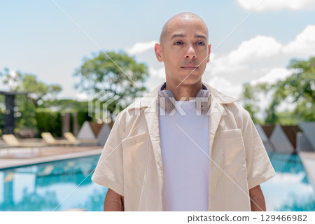 Latin bald man poolside in summer outfit, wellness lifestyle, vacation and outdoor portrait concept 129466982
