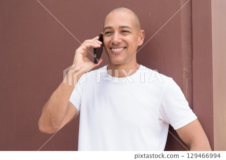 Studio style portrait of bald Hispanic man using mobile phone Studio style portrait of bald Hispanic man using mobile phone 129466994