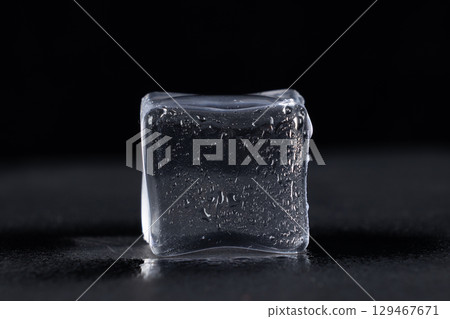 Clear ice cube set against a dark, possibly black, background. Clear ice cube set against a dark, possibly black, background. 129467671