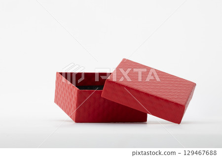 An open red gift box with its lid slightly askew, set against a clean white background 129467688
