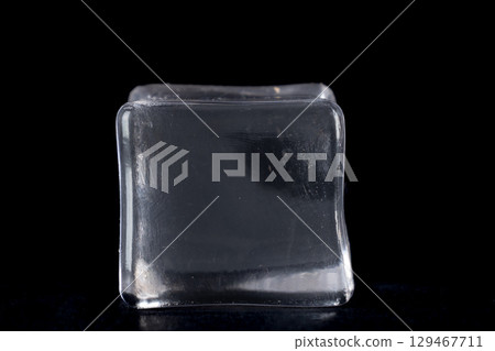 The ice cube is translucent with a slight sheen, suggesting a smooth, wet surface 129467711