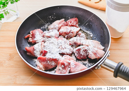 Sift flour over the seasoned pork 129467964