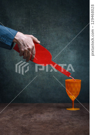 A man's hand holds a cardboard bottle over a glass A man's hand holds a cardboard bottle over a glass 129468028