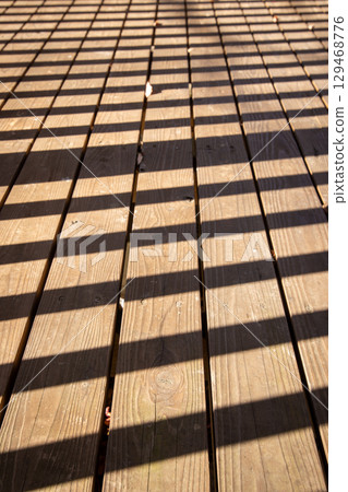 陽光透過木質甲板，形成格子狀的陰影圖案 129468776