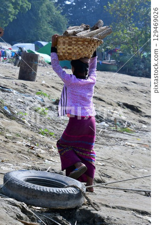 Myanmar, Mandalay, Ayeyarwady River, woman carrying thanaka sunscreen 129469026