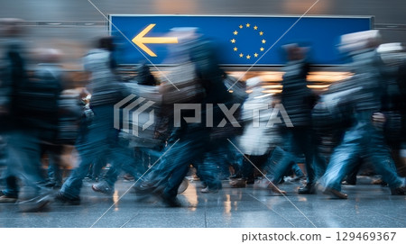Crowd moving past directional sign for Schengen area in airport during busy travel hours 129469367