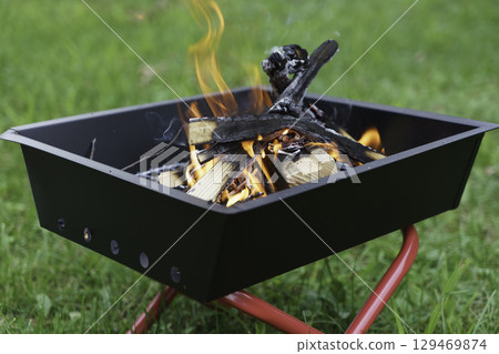 Bonfire burning on the grass at a campsite 129469874