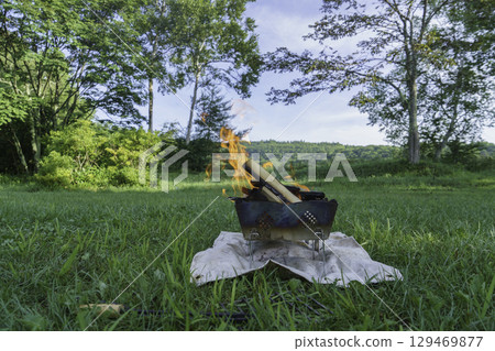 Bonfire burning on the grass at a campsite 129469877