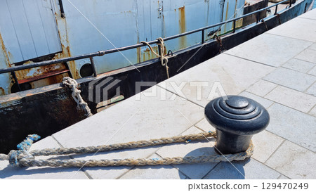 Boat rope tied to a black bollard Boat rope tied to a black bollard 129470249