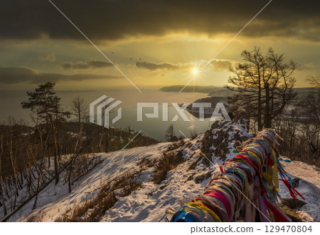 Top view over lake Baikal and the Angara river from Chersky stone in Listvyanka village at sunset. Winter landscape. Top view over lake Baikal and the Angara river from Chersky stone in Listvyanka village at sunset. Winter landscape. 129470804