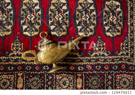 Magic lamp from the story of Aladdin with Genie isolated on red carpet. Magic lamp from the story of Aladdin with Genie isolated on red carpet. 129470811