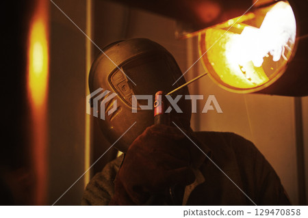 Male in face mask welds with welding 129470858