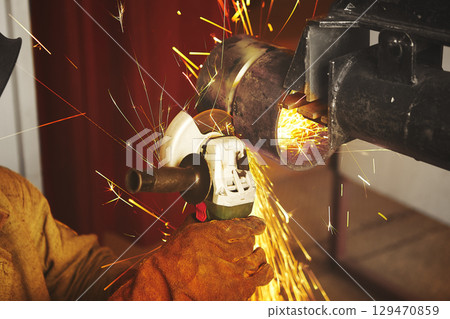 Close-up of worker cutting metal with grinder. Close-up of worker cutting metal with grinder. 129470859