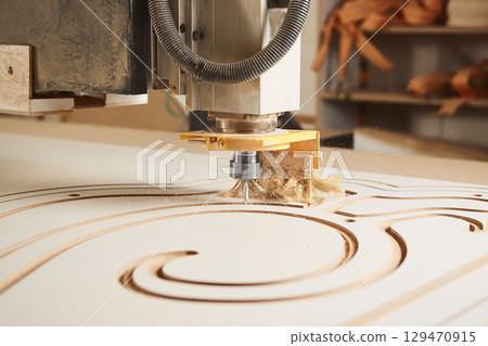 Numerically controlled woodworking machine cuts rounded complex lines on the canvas. Computer numerical control. CNC. Numerically controlled woodworking machine cuts rounded complex lines on the canvas. Computer numerical control. CNC. 129470915
