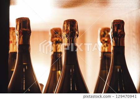 Close-Up View of Champagne Bottles Lined Up on Wooden Shelf Close-Up View of Champagne Bottles Lined Up on Wooden Shelf 129470941