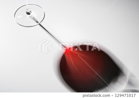 Black and red reflection of wineglass on thin stem. 129471017