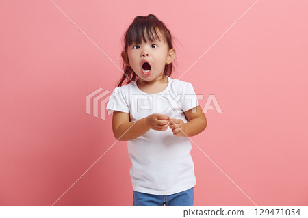Cute little child looks at the camera in surprise, being struck by unexpected news. An emotional three years old girl expresses surprise, does not believe her eyes. 129471054