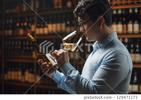 Professional Wine Expert Evaluating Quality and Checking Bottle Label in Cellar Professional Wine Expert Evaluating Quality and Checking Bottle Label in Cellar 129471171