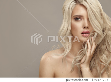 Much attractive blonde woman with long healthy curly hair on beige isolated with free copy space 129471204