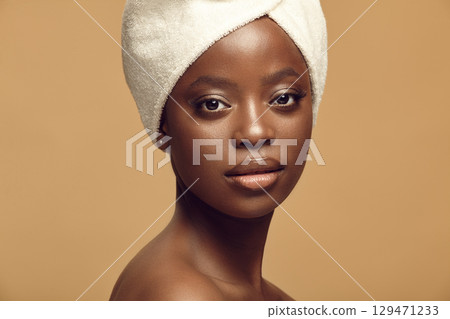 Headshot close up portrait of beautiful African American woman having healthy and clean skin tone on a beige isolated background. 129471233