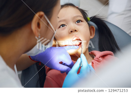 Child Girl Undergoing Routine Dental Check-Up With Female Dentist in Clinic 129471253