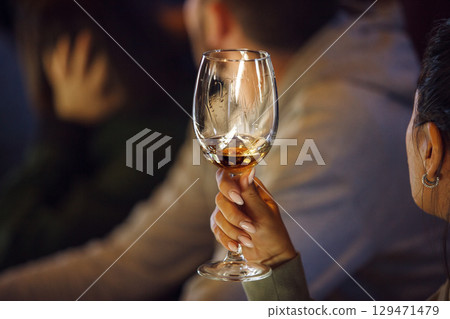 Close-Up of an Attendee Sampling Wine at Tasting Course in an Evening Setting 129471479