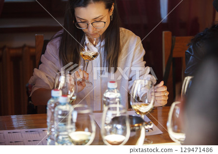 Woman Sitting at Table With Wine Glasses and Semmling it  129471486