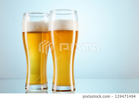 Yellow alcoholic fizzy drink, brew fills glasses to brim. 129471494