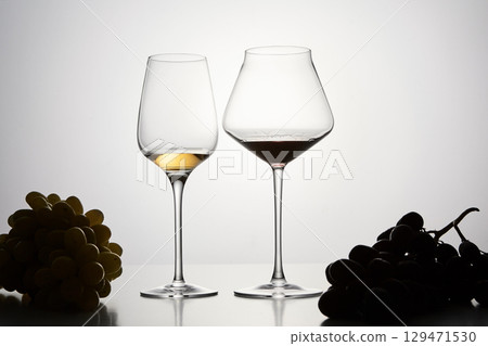 Red, white wine in stemware with dark grapes. Red, white wine in stemware with dark grapes. 129471530