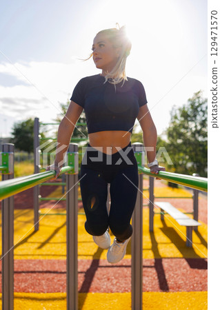 Woman Performing Outdoor Exercise with Strength Training on Fitness Station Woman Performing Outdoor Exercise with Strength Training on Fitness Station 129471570