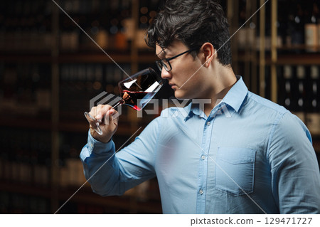 Professional Sommelier Evaluating Red Wine in Cellar Environment 129471727