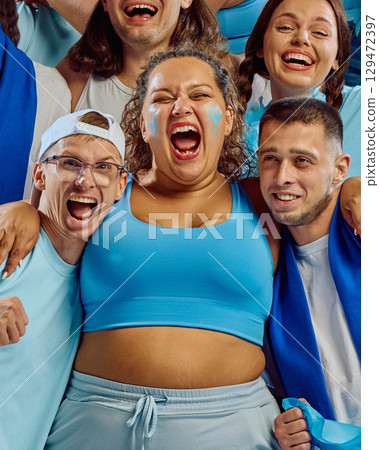 Group of fans embracing and cheering in blue sports outfits 129472397