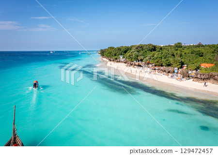 Tourists enjoy Nungwi Beach, Zanzibar, with its turquoise water and white sand Tourists enjoy Nungwi Beach, Zanzibar, with its turquoise water and white sand 129472457