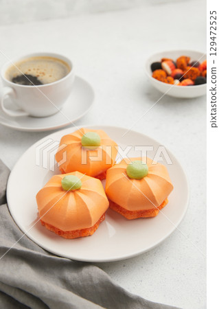 White ghost shaped meringue cookies with black eyes, stacked on a dark gray plate with a napkin 129472525