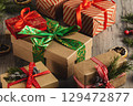 Christmas traditional gift boxes decorated with spruce twigs and cones on a wooden table, selective focus. 129472877