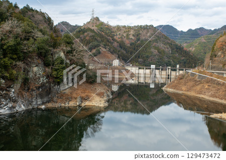 A quiet dam lake reflecting the winter mountains at Akaku Dam in Chichibu, Saitama. 129473472