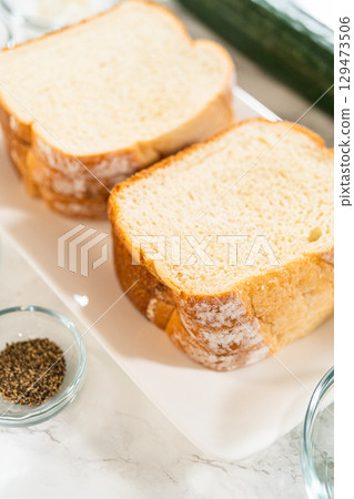 Top view of soft bread slices with seasoning bowls including black pepper and salt, essential for mini cucumber sandwich flavoring. Great for cooking blogs and prep tutorials. Top view of soft bread slices with seasoning bowls including black pepper and salt, essential for mini cucumber sandwich flavoring. Great for cooking blogs and prep tutorials. 129473506