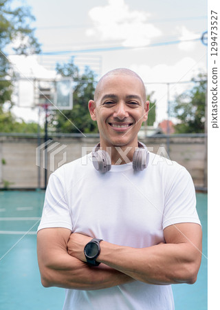 Confident Latin man on outdoor basketball court, sports fitness and athletic lifestyle portrait 129473527