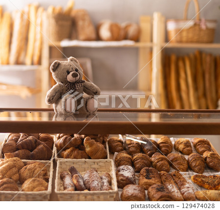Toy bear is placed on glass display case with pastry, decor of interior space to attract attention Toy bear is placed on glass display case with pastry, decor of interior space to attract attention 129474028