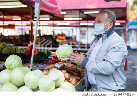 Man in mask buying cabbage in market Man in mask buying cabbage in market 129474029