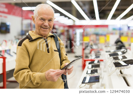 senor man pensioner buying modern tablet digital in showroom of digital electronic goods store senor man pensioner buying modern tablet digital in showroom of digital electronic goods store 129474030