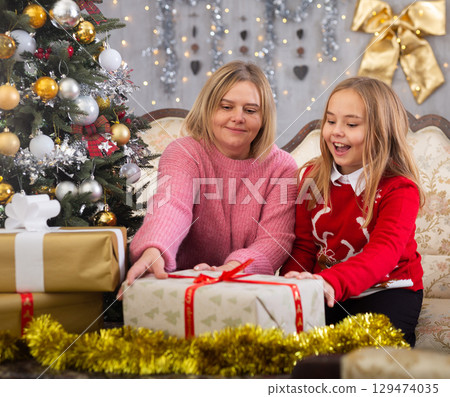 Portrait of smiling mom with little daughter during christmas celebration Portrait of smiling mom with little daughter during christmas celebration 129474035