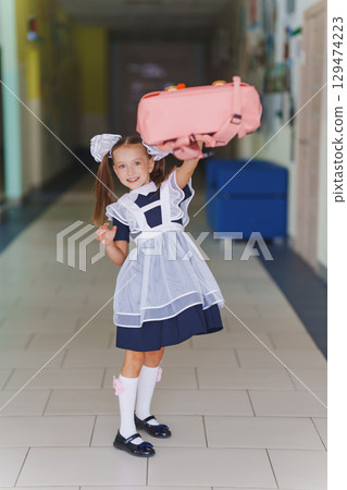 Happy cute little girl in school uniform in school corridor 129474223