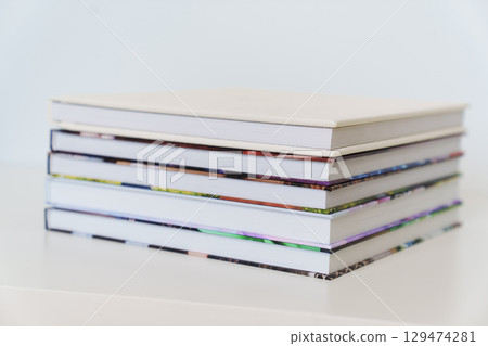 Folded photo books with white leather and multi-colored photo covers. 129474281