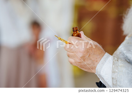The priest performs chrismation at the sacrament of baptism. 129474325