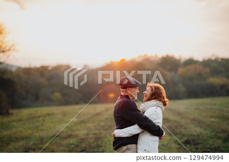 Senior couple embracing in autumn sunset light. 129474994