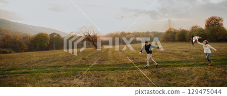 Senior couple flying a kite during warm autumn evening. 129475044