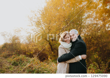 Romantic walk through fall forest by senior couple. Romantic walk through fall forest by senior couple. 129475090